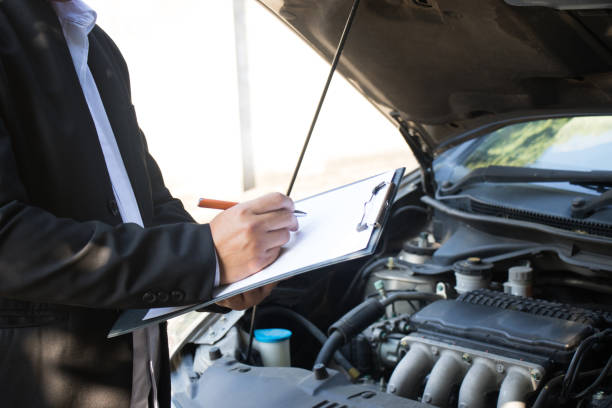 istock Side view of writing on clipboard while insurance agent examining car 902390876