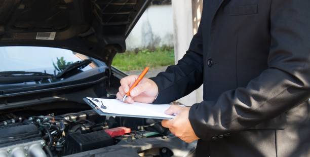 istock Side view of writing on clipboard while insurance agent examining car 902390886