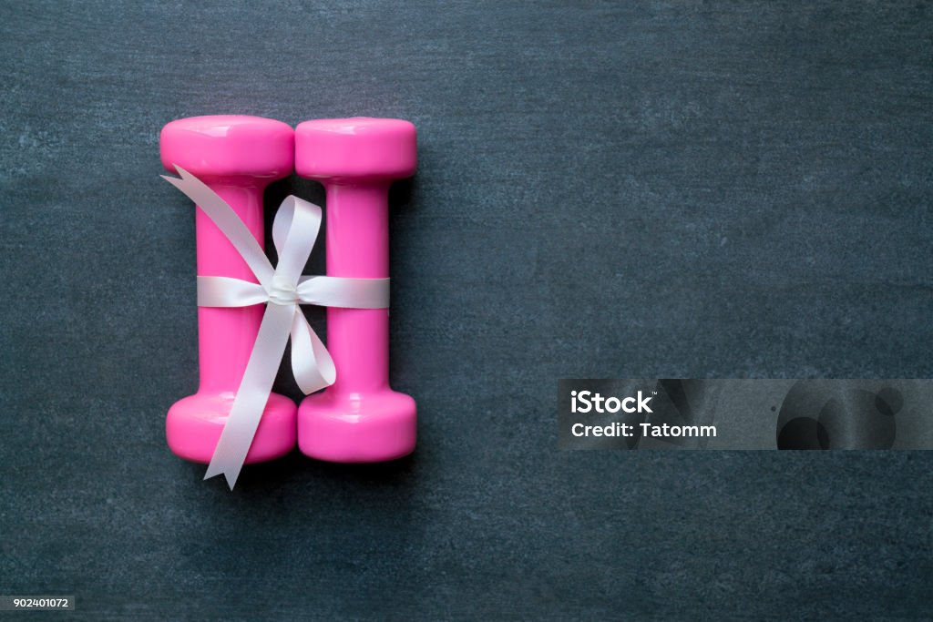 zwei rosa Hantel mit weißen Geschenk Bogen auf einem schwarzen Tisch Hintergrund, Sport und gesundes Konzept - Lizenzfrei Geschenk Stock-Foto