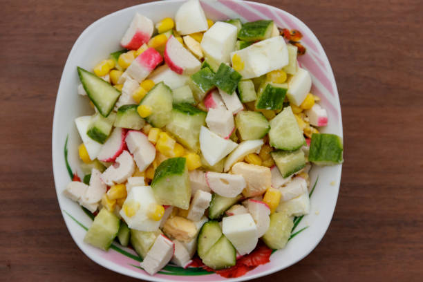 istock Salad with crab sticks, sweet corn, cucumber and eggs on wooden table 902407582