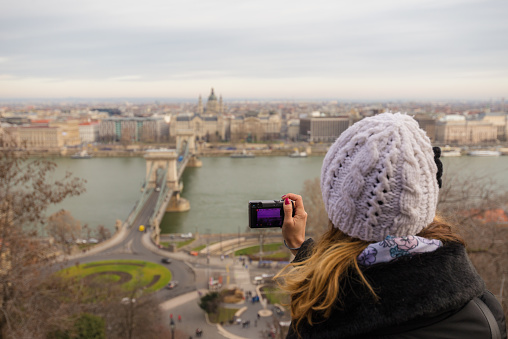 Young woman is taking a photo of Chain Bridge from top. Chain bridge is  suspension bridge that spans the River Danube in Budapest, Hungary.