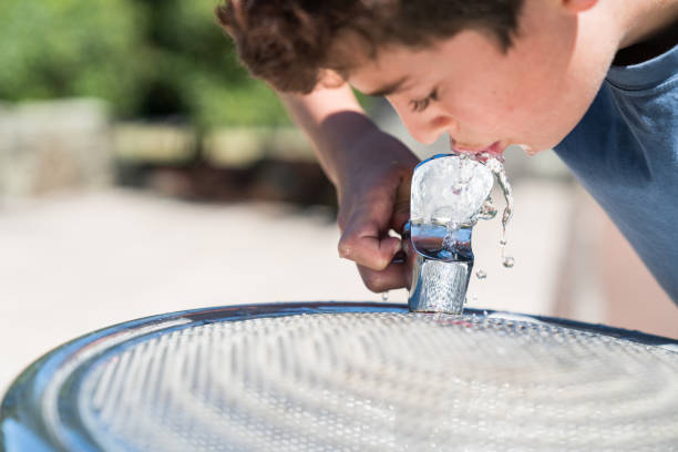 istock Boy at water fountain enjoying a cool drink 902420348