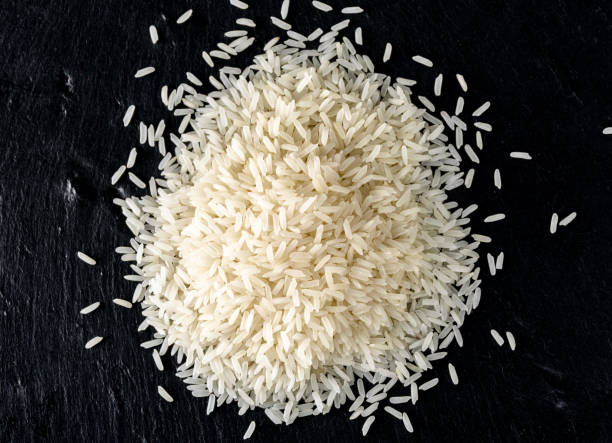 weißer reis haufen isoliert auf schwarzem hintergrund, ansicht von oben - coarse rice stock-fotos und bilder