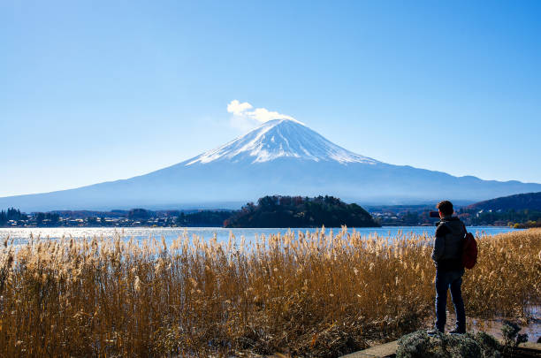 Photographer man standing outdoor photography by mobile amidst beautiful nature of Mt. Fuji at Yamanashi in Japan with lake kawaguchiko. Travel and Attractions Concept. Photographer man standing outdoor photography by mobile amidst the beautiful nature of Mt. Fuji at Yamanashi in Japan with lake kawaguchiko. Travel and Attractions Concept. Lake Kawaguchi stock pictures, royalty-free photos & images