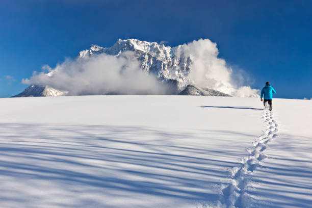 hombre caminando en la nieve frente a monte zugspitze - zugspitze mountain mountain germany sky fotografías e imágenes de stock