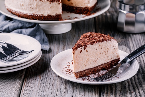 A piece of no-bake chocolate cheesecake on a plate on  wooden rustic background