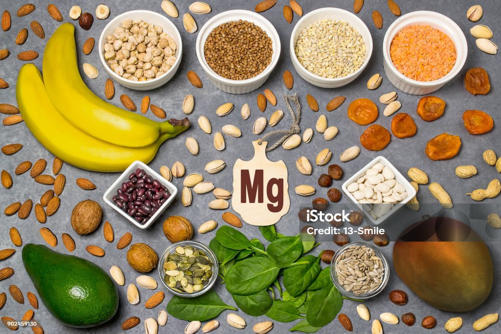 Food is source of magnesium (Mg) Food is source of magnesium (Mg). Various natural food rich in vitamins. Useful food for health and balanced diet. Prevention of avitaminosis. Small cutting board with name of magnesium. Top view Magnesium Stock Photo