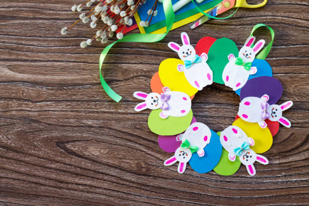 istock Children's Easter gift wreath with colorful eggs and Easter bunnies. Hand-made. Children's art project for children. Craft for kids. Flat lay. Top view with copy space. 902461902