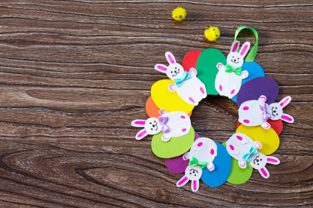 istock Children's Easter gift wreath with colorful eggs and Easter bunnies. Hand-made. Children's art project for children. Craft for kids. Flat lay. Top view with copy space. 902461918