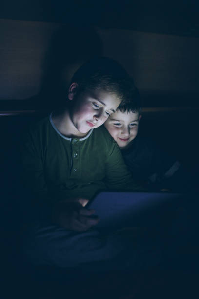 istock Kids secretly reading playing with digital tablet 902465940