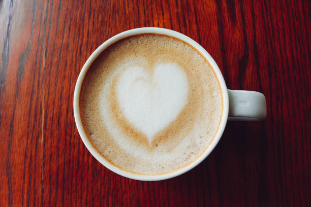 istock Latte coffee on coffee shop with heart pattern in a white cup on wooden table background 902468546