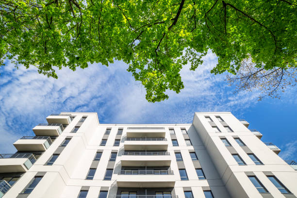 istock New modern white apartment building against green tree 902474560