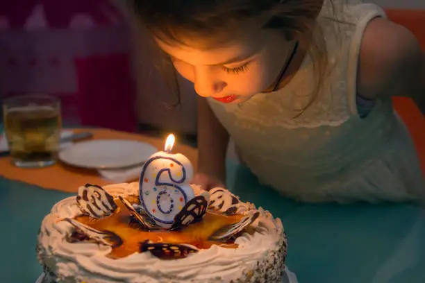 Children's birthday party.Girl blows out a candle,making a wish.