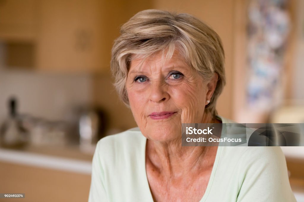 beautiful portrait of pretty and sweet senior mature woman in middle age around 70 years old smiling happy and friendly at home kitchen in aging and lifestyle concept 70-79 Years Stock Photo