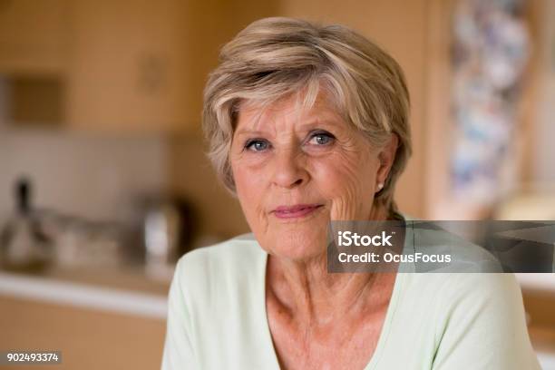 Beautiful Portrait Of Pretty And Sweet Senior Mature Woman In Middle Age Around 70 Years Old Smiling Happy And Friendly At Home Kitchen In Aging And Lifestyle Concept Stock Photo - Download Image Now