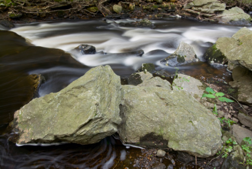 Two main rocks with flowing summer water in Connecticut behind them.