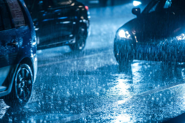 conducir en el camino mojado en la lluvia con faros de coches - mojado fotografías e imágenes de stock