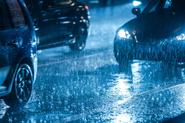 cars driving on wet road in the rain with headlights - rain imagens e fotografias de stock