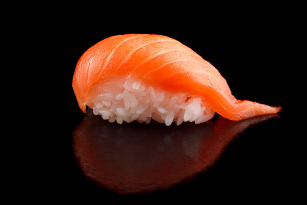 istock Appetizing sushi rolls with salmon on a black background close-up. 902497644