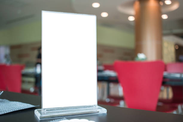 istock Mock up white Label for blank menu frame in Bar restaurant cafe., Stand for booklets with  sheets paper tent card on table cafeteria, blurred background insert for text of customer. Space for texting. 902507944
