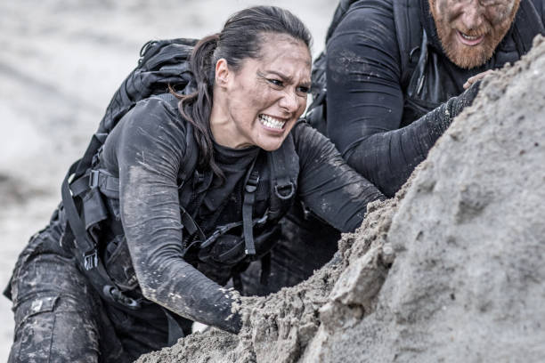 executar ruiva morenas e masculinos femininos membros militares treinando duro e ajudando uns aos outros em uma colina de areia - armed forces war military macho - fotografias e filmes do acervo