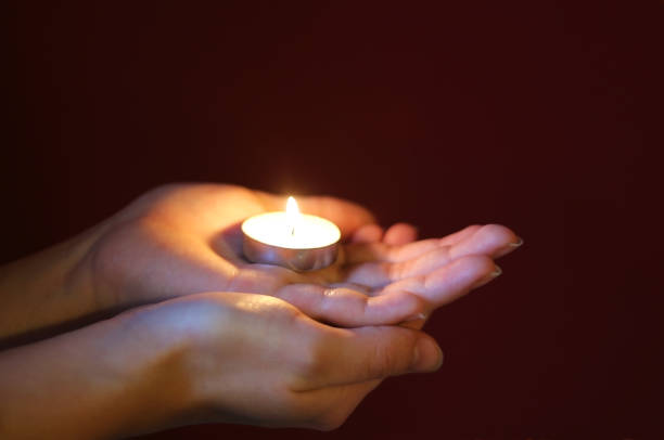 istock hands of a woman holding a lit tea light 902528026