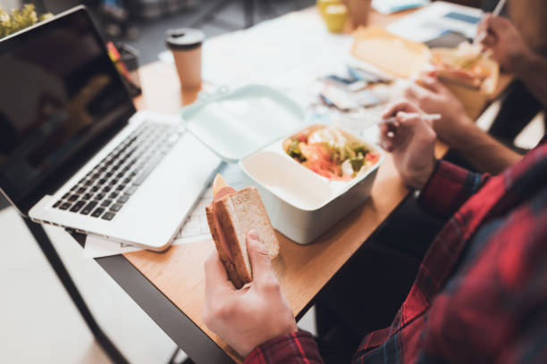 istock A girl and two guys have a snack at the office. 902531992