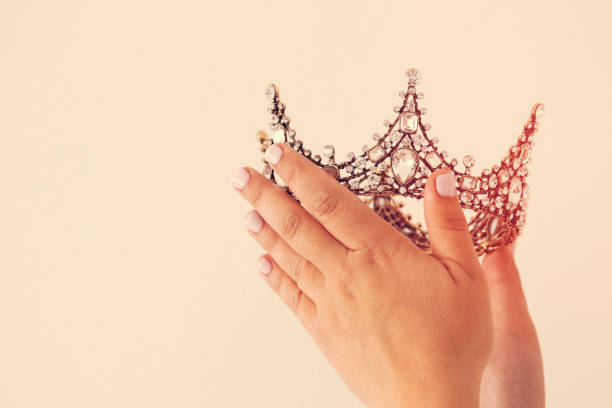 istock Woman's hand holding a crown for show victory or winning first place. White background. Copy space. Isolated. 902532550