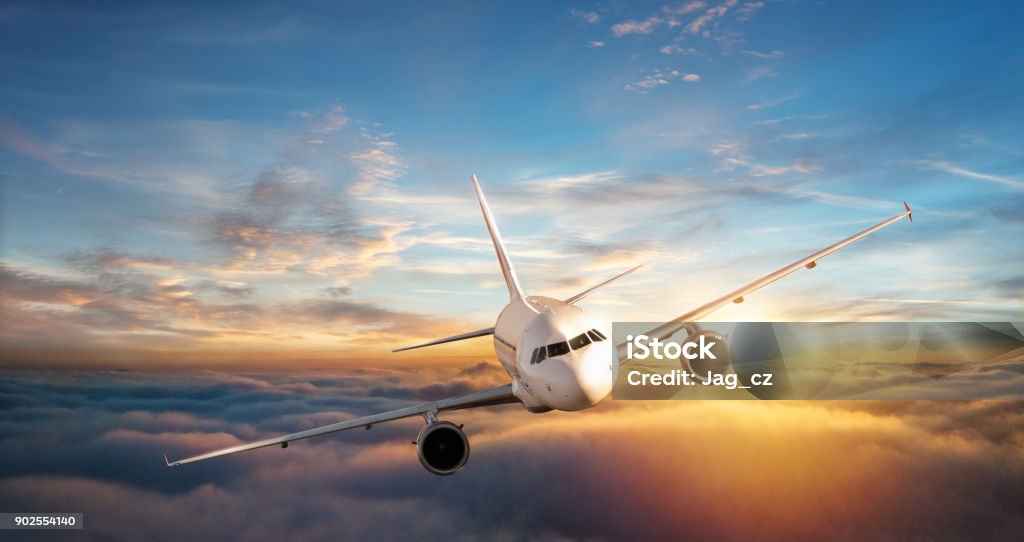 Commercial airplane jetliner flying above clouds in beautiful sunset light. Commercial airplane jetliner flying above clouds in beautiful sunset light. Travel and business concept Aerial View Stock Photo