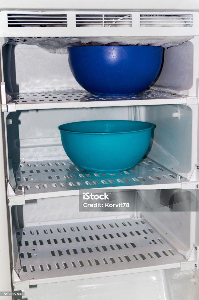 defrost the refrigerator with hot water blue basins in the refrigerator to defrost Appliance Stock Photo