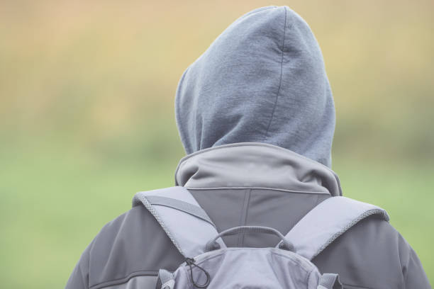 istock Man with hood and backpack from behind with soft bokeh 902565610