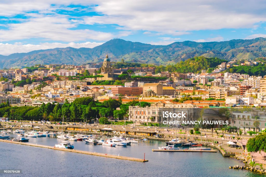 Messina, Sicily, Italy Cityscape of Messina, Sicily, Italy. Multi colored image with buildings, cathedral, mountains, blue sky with clouds, boats and yachts in the harbor or cruise port of Messina. Messina Stock Photo