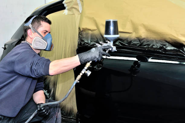 istock Professional car painter working at a black vehicle. 902579616