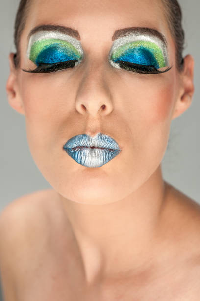 close up on a women with multi colored make-up and eyes closed on a light grey background