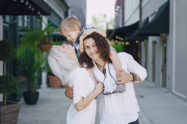 beautiful young family dad mom and a little boy with blond hair walking around the city and enjoying the sunshine, multi family black and white three way kiss stock pictures, royalty-free photos & images