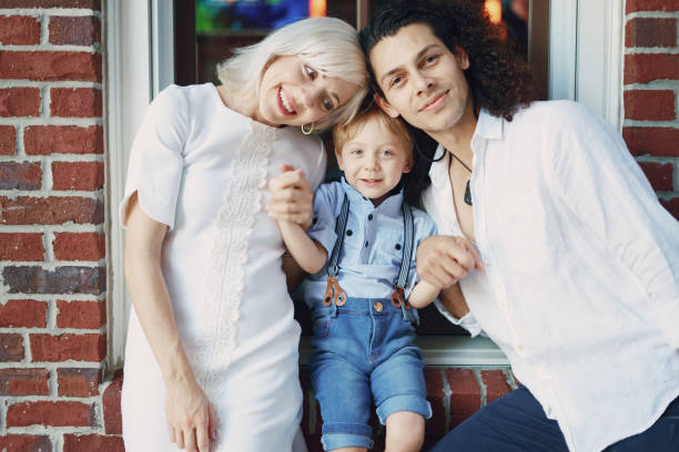 beautiful young family dad mom and a little boy with blond hair walking around the city and enjoying the sunshine, multi family black and white three way kiss stock pictures, royalty-free photos & images