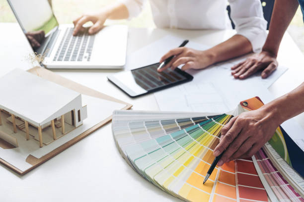 istock Two interior design or graphic designer at work on project of architecture drawing with work tools and color swatches, colour chart, color samples for selection, renovation and technology concept 902592220