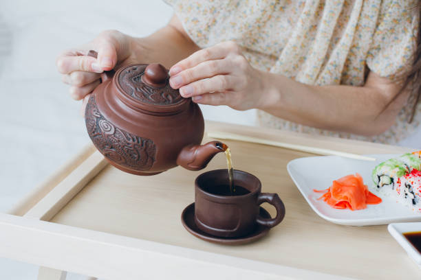istock Woman drinking green tea and eating sushi 902598642