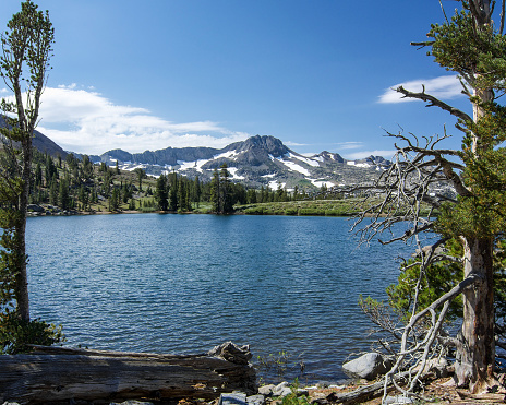 Sierra Nevada's Winnemucca Lake at mid-day in the summer, with rocks,  the mountains and a few pine trees, and clouds in the backgroud