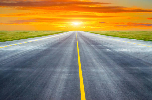 istock Runway and road goes into the horizon at sunset dawn. 902607160
