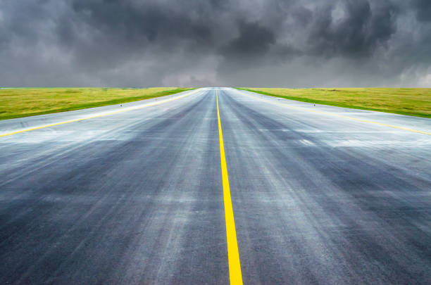 istock Runway and road goes into the horizon at cloudy sky. 902607278