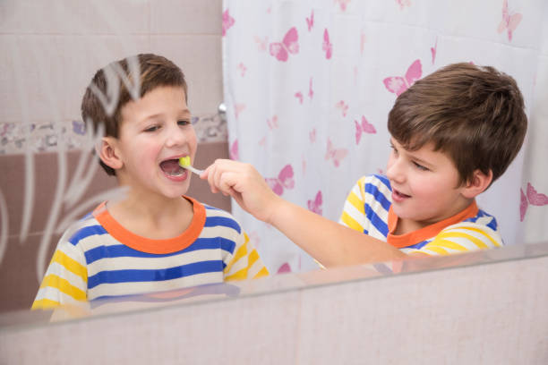 istock Older brother learning to clean the teeth for younger brother 902613240