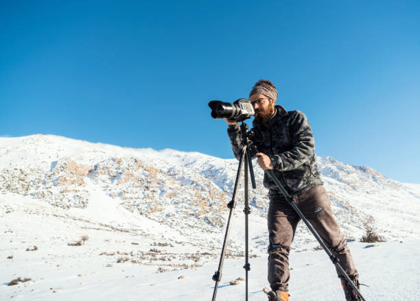 Outdoor Photographer taking pictures on the snowy mountains, Taurus Mountains, Antalya, Turkey. He is using a medium format digital camera mounted on a tripod