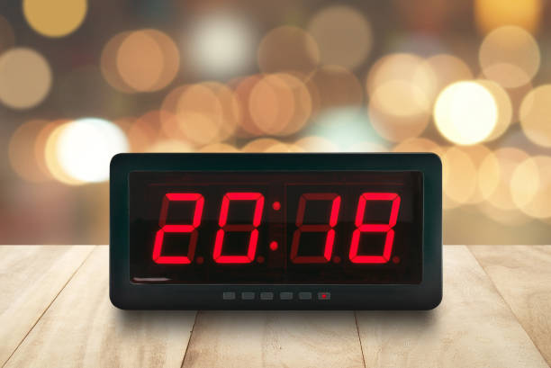 czerwone światło led podświetlone numery 2018 na cyfrowej elektrycznej budziku twarz na brązowym drewnianym blacie z rozmytym kolorowymi światłami świątecznymi bokeh tle - table time clock clock face zdjęcia i obrazy z banku zdjęć