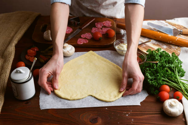 o chef faz um coração de pizza para o feriado do dia dos namorados. clássico italiano pizza com salame e mussarela - cheese making - fotografias e filmes do acervo