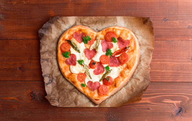 シェフは、バレンタインの日の休日のためピザ心をなります。サラミとモッツァレラチーズの古典的なイタリアのピザ - cheese making ストックフォトと画像