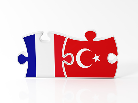 Jigsaw puzzle pieces textured with French and Turkish flags on white. Horizontal composition with copy space. Clipping path is included.