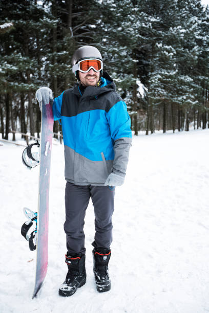 istock Portrait of young man holding snowboard 902647548