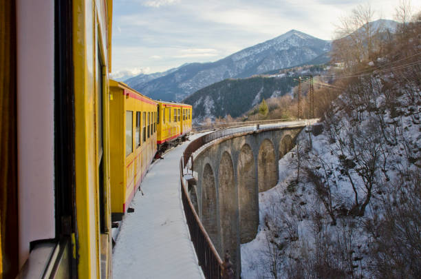 istock Yellow train passing on a bridge in a snowy landscape 902648078