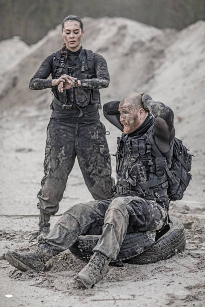 istock Female drill instructor training shaved male soldier with tires outdoors in the mud 902651138